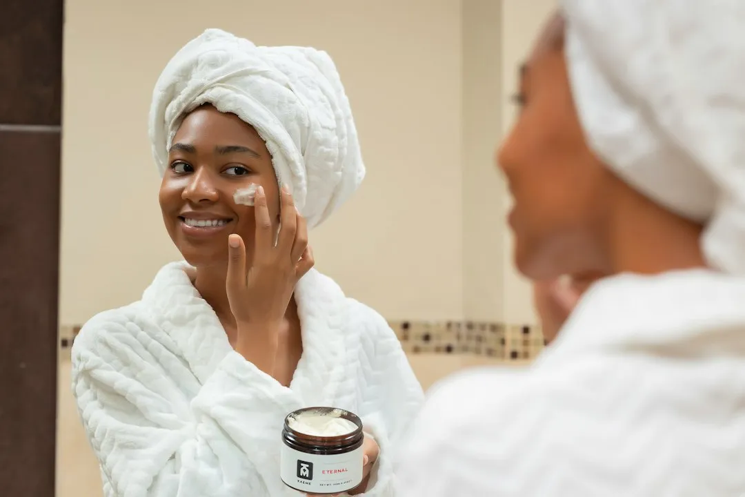 Frau trägt reichhaltige Pflegecreme auf – Bodybutter richtig anwenden