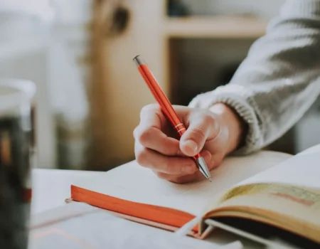 Hand schreibt mit Stift in ein Notizbuch – Schreiben vor dem Schlafen hilft beim Einschlafen
