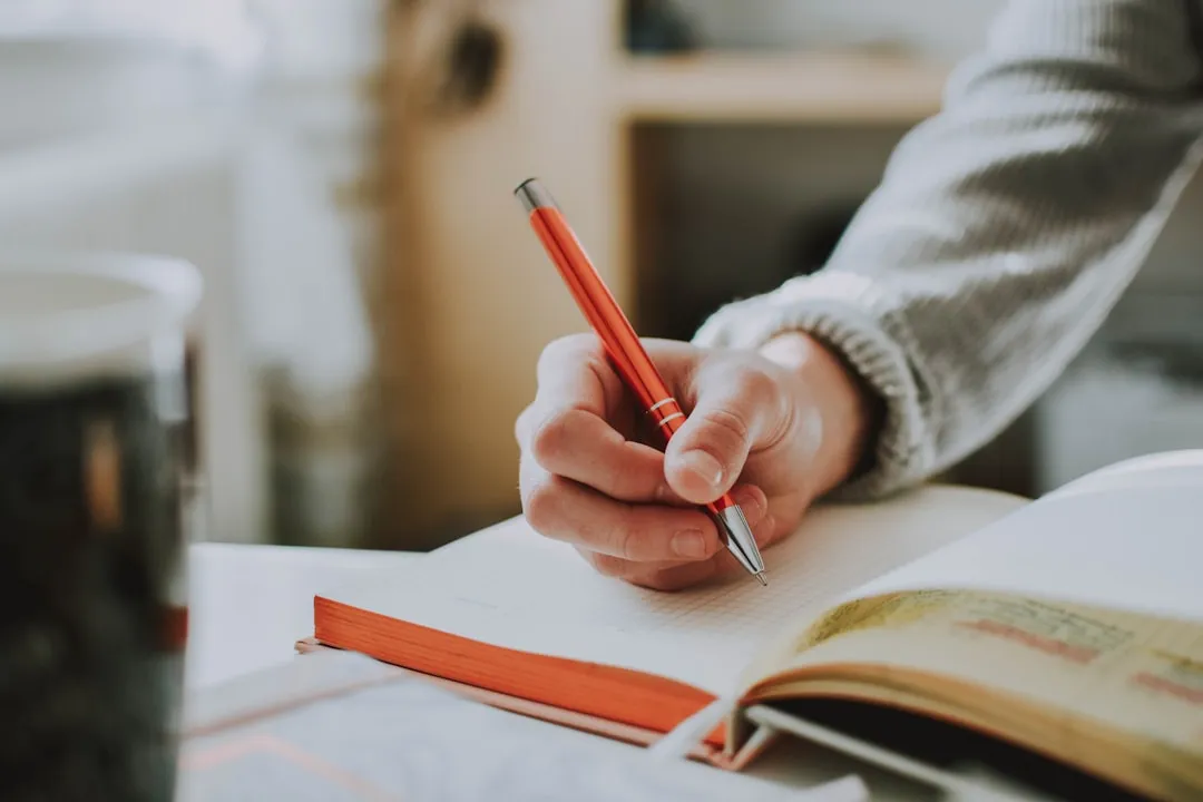 Hand schreibt mit Stift in ein Notizbuch – Schreiben vor dem Schlafen hilft beim Einschlafen
